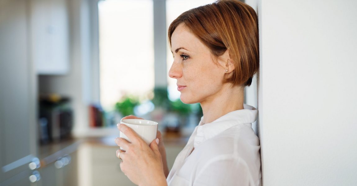 a young woman with cup of coffee standing indoors XWM64N7 scaled